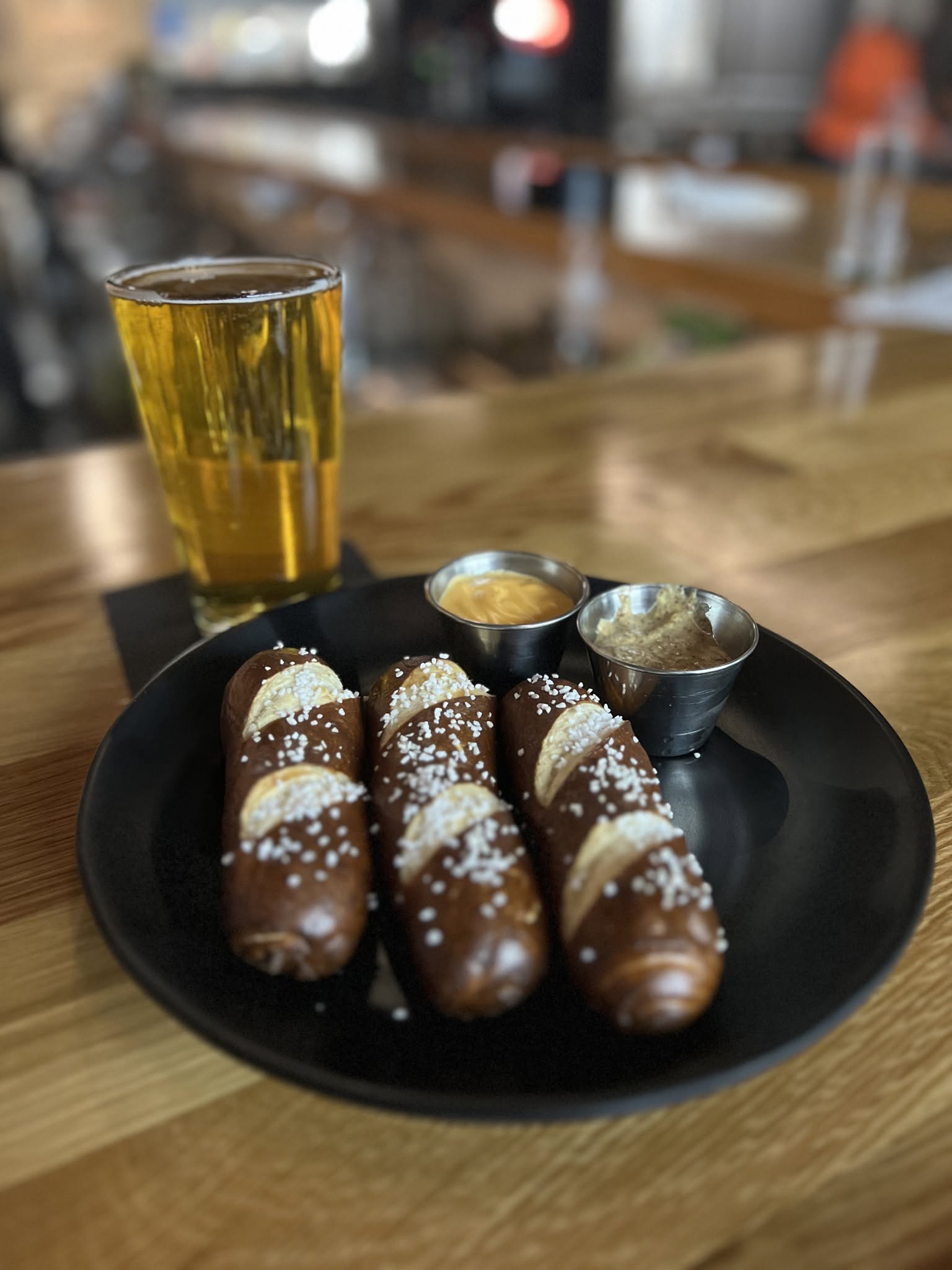 Pub house pretzels with cheese sauce and creole mustard beside a pint.